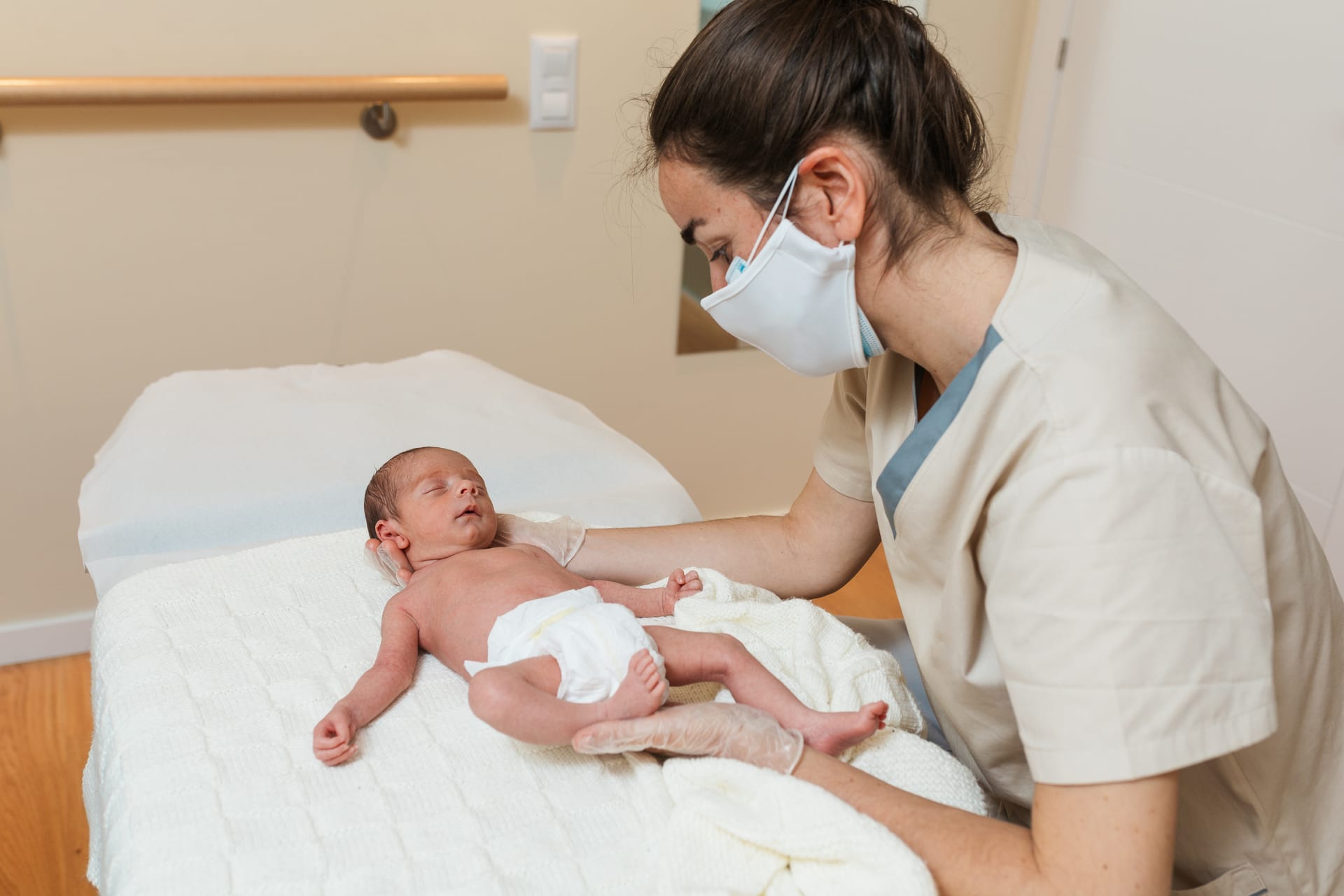Practitioner gently treating a newborn baby lying on a treatment table